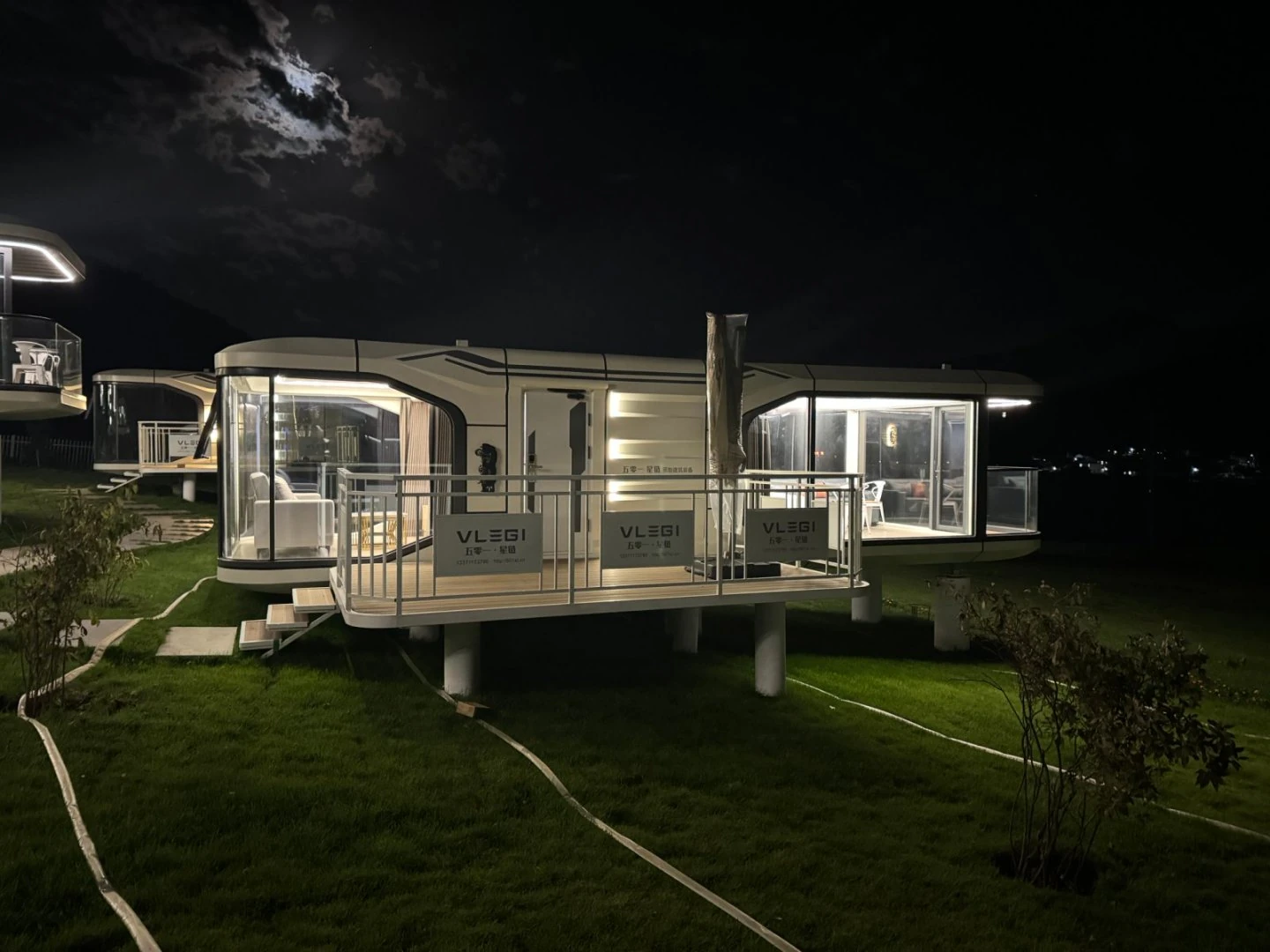 Mobilhaus Liu Tiny House, bahçede gece aydınlatmalı dış görünüm.